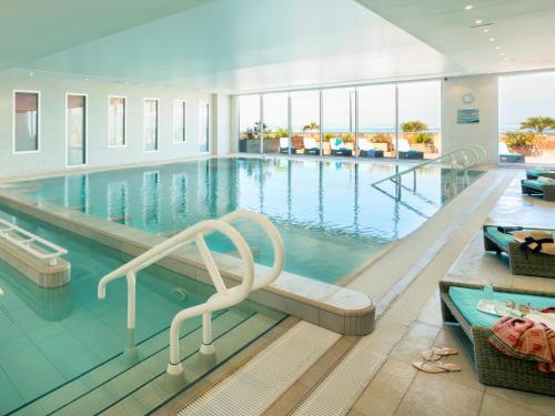 a large swimming pool with a chair in the middle at Hôtel de la Baie - Thalassothérapie PREVITHAL in Donville-les-Bains