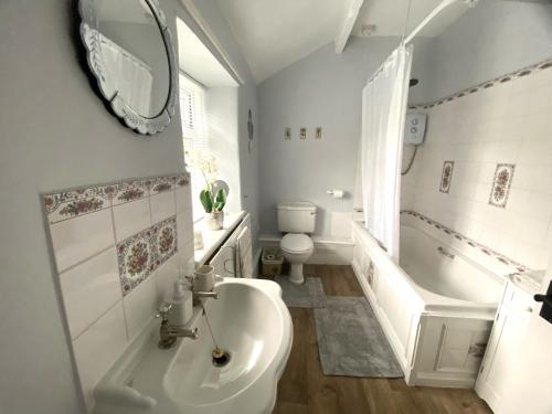 a bathroom with a sink and a tub and a toilet at Holme House Cottage in Oakworth