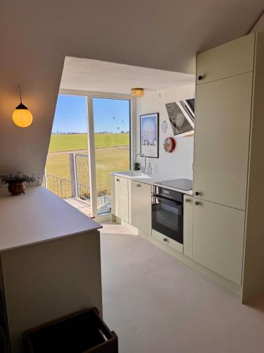 a kitchen with white cabinets and a large window at Large holiday apartment in Ebeltoft