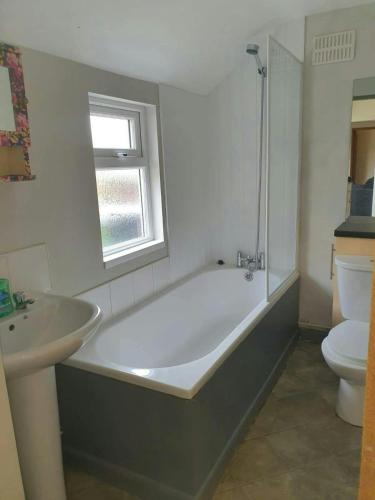a bathroom with a tub and a sink and a toilet at Beautiful House in Stoke in Audley