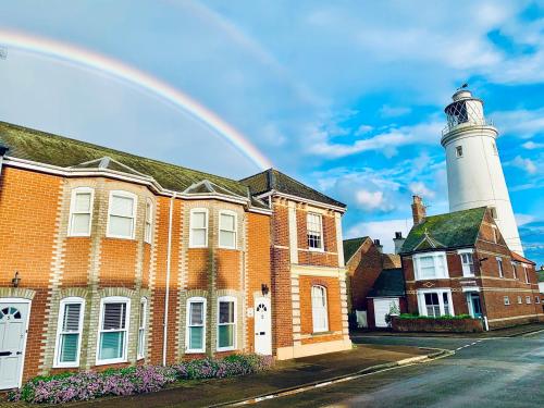 a rainbow over a brick building with a lighthouse at Cosy Nook, Southwold in Southwold