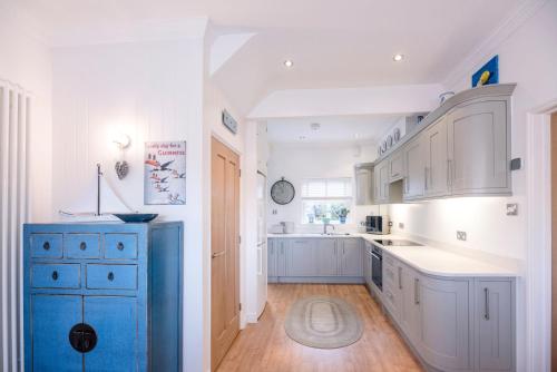 a kitchen with white cabinets and a blue island at Cosy Nook, Southwold in Southwold