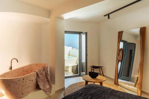 a bedroom with a bath tub and a mirror at Gazelle Living in Imerovigli