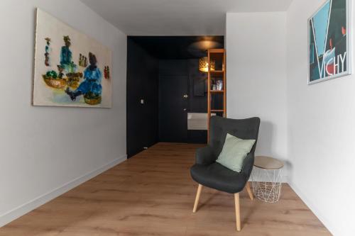 a room with a chair and a painting on the wall at L'Alquié - Appartement design hyper centre in Vichy