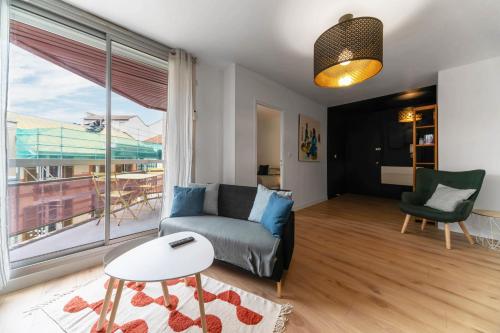a living room with a couch and a large window at L'Alquié - Appartement design hyper centre in Vichy