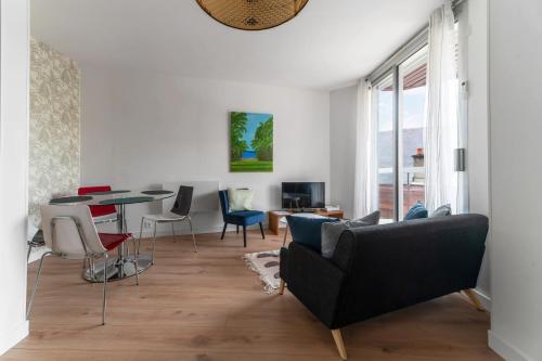 a living room with a black couch and a table at L'Alquié - Appartement design hyper centre in Vichy