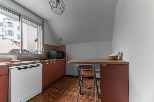 a small kitchen with a table and a sink at L'Alquié - Appartement design hyper centre in Vichy