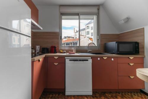 a kitchen with a white dishwasher and a window at L'Alquié - Appartement design hyper centre in Vichy