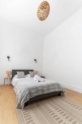 - une chambre blanche avec un lit et un tapis dans l'établissement Le Larbaud - Appartement calme en centre ville, à Vichy