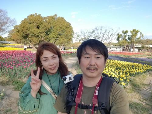 a man and a woman standing in a field of flowers at NINN102 - Osaka Itami Airport Guest House 大阪国際空港 伊丹空港 ITM ゲストハウス ニン in Ikeda