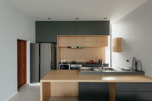 a kitchen with green cabinets and a stainless steel refrigerator at Casa Jasmine H2 l Private Pool 3BR Near Nimman in Chiang Mai