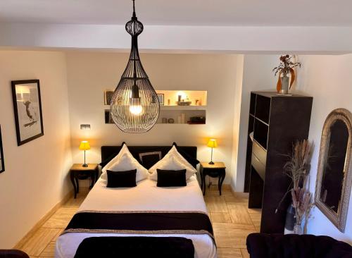 une chambre avec un lit et un lustre dans l'établissement Le Mas des Mirabelles, à Cabannes