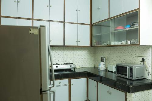a kitchen with white cabinets and a microwave at Woodpecker Apartments Hauz khas in New Delhi