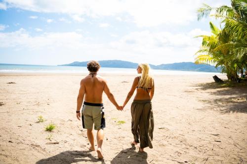 a man and a woman walking on the beach at 8-min Walk to Beach with Pool & Golf in Pochote