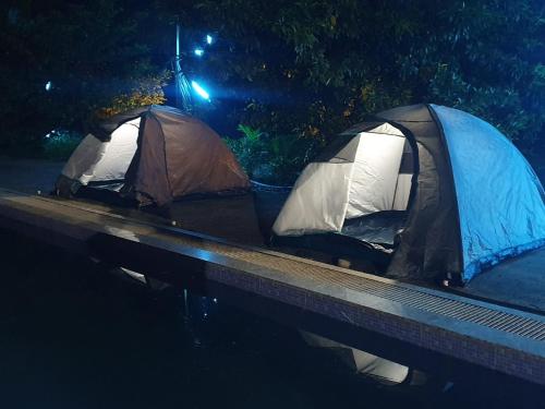 two tents on the side of a river at night at Kalwars Millennials Park in Karjat