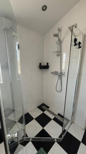 a bathroom with a shower and a black and white checkered floor at De Os aan de Dijk 2 in Grafhorst
