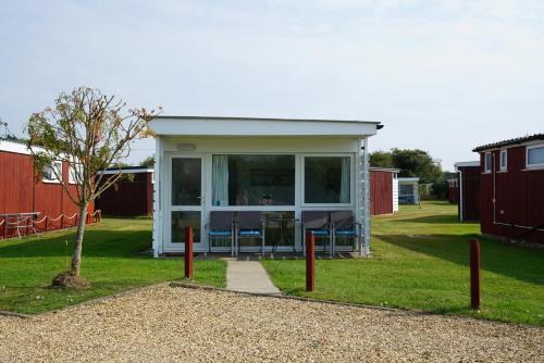 a tiny house in a yard with a porch at Sea Lavender Holiday Chalet, close to sandy beach in Heacham