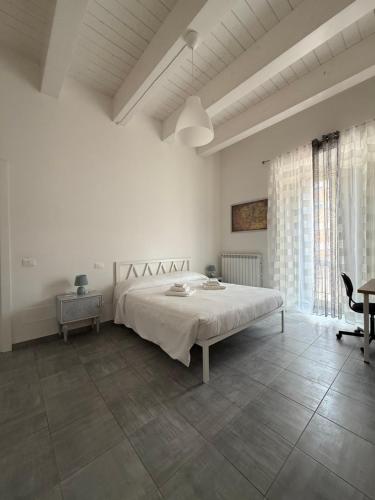 Un dormitorio blanco con una cama grande y una mesa. en Residenza Antinori, en LʼAquila