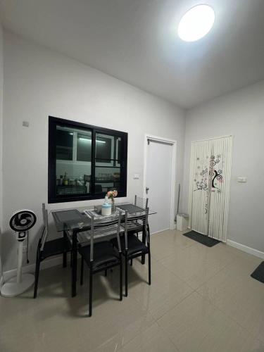 a dining room with a table and chairs and a television at Sai's cozy house in Khanom
