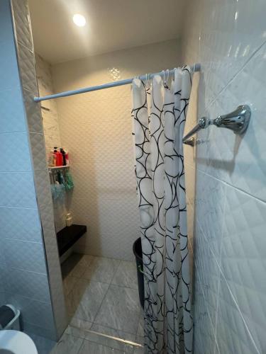 a shower with a shower curtain in a bathroom at Sai's cozy house in Khanom