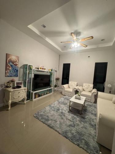 a living room with white furniture and a ceiling fan at Sai's cozy house in Khanom