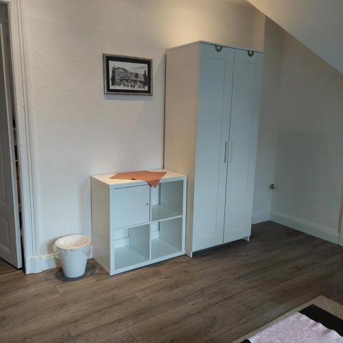 a white cabinet in a room with wooden floors at Zimmervermietung B&B in Neumünster