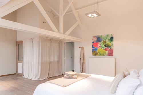 a bedroom with a white bed and a painting at Casa Tintos in Sint-Amands