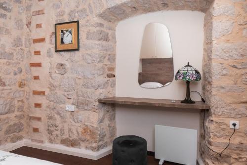 a bedroom with a stone wall and a mirror at Sizgoric Palace Suites Sibenik in Šibenik