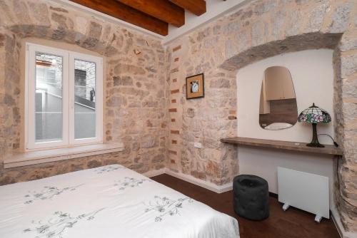 a bedroom with stone walls and a bed and a window at Sizgoric Palace Suites Sibenik in Šibenik