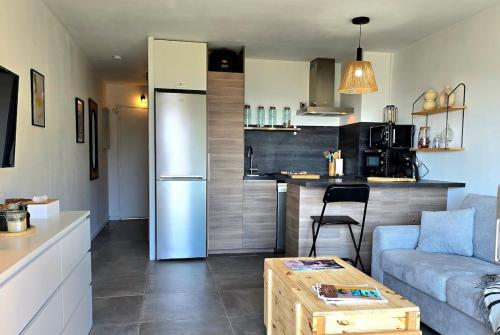 une cuisine et un salon avec un canapé et une table dans l'établissement La Baie - Studio neuf avec balcon vue mer, à 5min de la mer avec parking - By AURAconciergerie, à La Ciotat