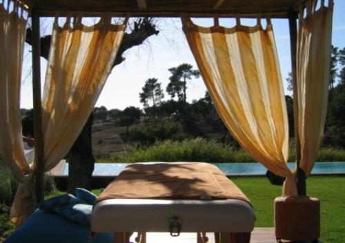 a bed sitting in a porch with curtains at Monte Do Areeiro in Coruche
