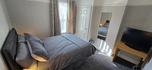a bedroom with a bed and a flat screen tv at Alexandra Park House in Belfast