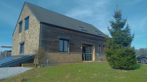 une maison en briques avec un arbre devant elle dans l'établissement Au Coeur des Champs, à Regniowez