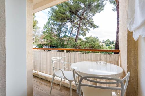 une table blanche et des chaises sur un balcon dans l'établissement Lou Pichot par Dodo à Cassis, à Cassis