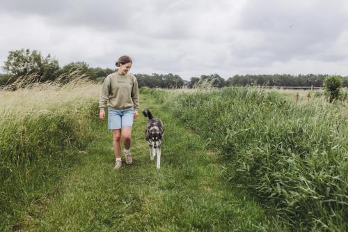 a woman walking her dog through a field at Safaritent in Kolham