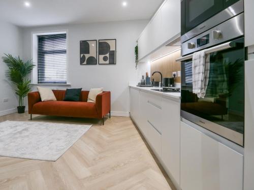 a living room with a red couch and a kitchen at Dwell Living North Bridge Apartments in Sunderland