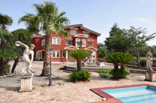 dom z palmami i posągami przed nim w obiekcie Villa Parco del Monte w mieście Cassano Jonio