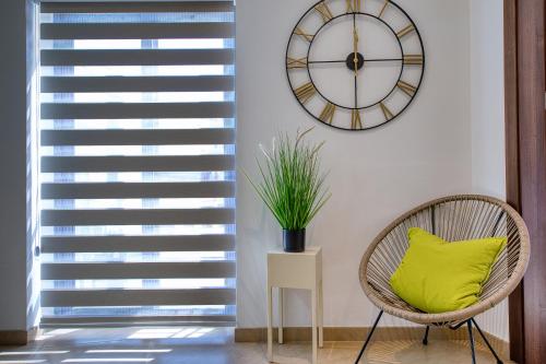 a chair with a green pillow in a room with a clock at Cozy Apartment minutes to seafront in Kalkara