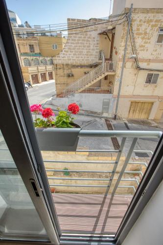 a view from the window of a balcony with flowers at Cozy Apartment minutes to seafront in Kalkara