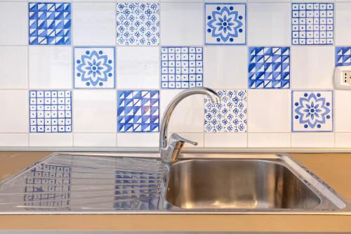 a sink in a kitchen with blue and white tiles at Il Belvedere Di Achille in Costa Paradiso
