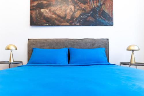 a bedroom with a blue bed and a painting on the wall at Exclusive Villa with Lake view-Private SPA in Galbiate