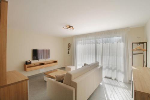 - un salon blanc avec un canapé et une télévision dans l'établissement New T3 with air conditioning 2 steps from the lake, à Aix-les-Bains