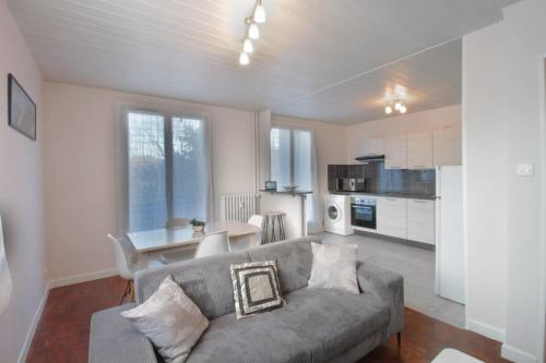 a living room with a gray couch and a kitchen at Pleasant T3 near the Thermes de Marlioz in Aix-les-Bains