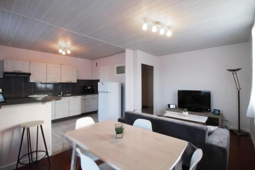 a living room with a table and a kitchen at Pleasant T3 near the Thermes de Marlioz in Aix-les-Bains