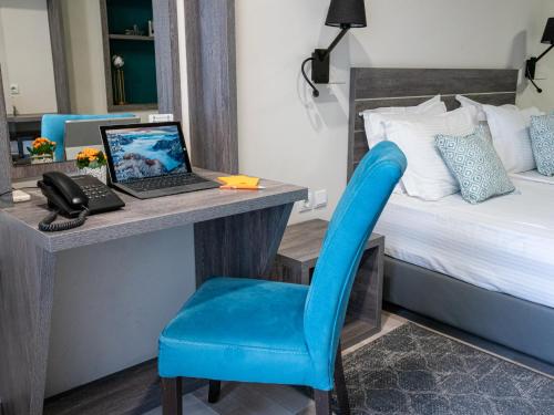 a bedroom with a desk with a laptop and a blue chair at SPA Hotel Olymp in Velingrad