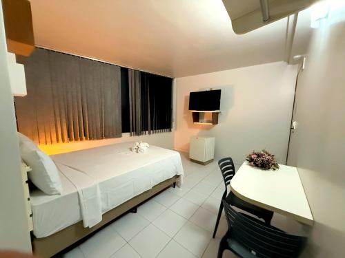 a bedroom with a bed and a desk and a television at Hotel Nacional in Arapiraca
