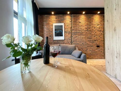 a table with a bottle of wine and two glasses at Copernicus Street Apartment - Broken Flowers and Twin Peaks in Toruń