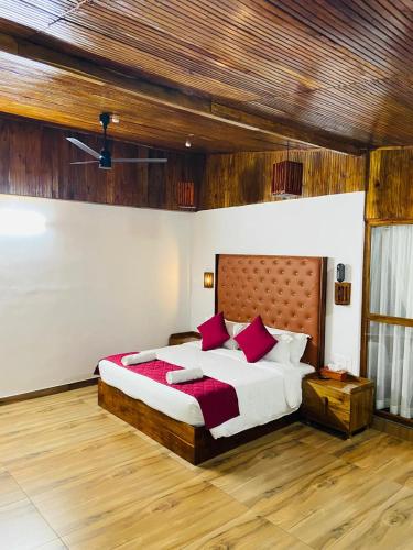 a bedroom with a large bed with red pillows at Peak Paradise Resort in Varkala
