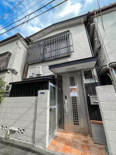 a white house with a door and a balcony at 大熊の家 028t in Tokyo