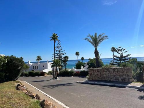 a driveway with a house and palm trees and the ocean at Beach Front Villa Al Andalus in Restinga Smir